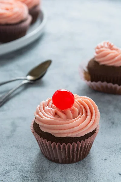 Chocolate cupcake dengan buttercream stroberi dan cherry di atas, makanan manis. — Stok Foto