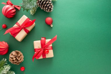 Noel yeşil arka planı, kış süslemeleri, hediye kutuları, köknar dalları, çam kozalakları ve kırmızı takılar. Boşluğu kopyala.