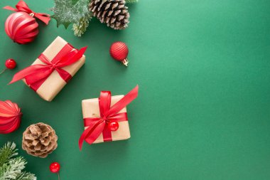 Noel yeşil arka planı, kış süslemeleri, hediye kutuları, köknar dalları, çam kozalakları ve kırmızı takılar. Boşluğu kopyala.