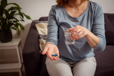 Elinde mavi haplar tutan bir kadın. Sağlık, beslenme takviyeleri, depresyon ve hastalıkların tedavisi