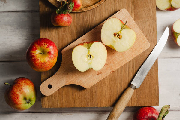 Красные яблоки, цельные и нарезанные на деревянной доске, образ жизни, вид сверху. Осенний абстрактный фон питания