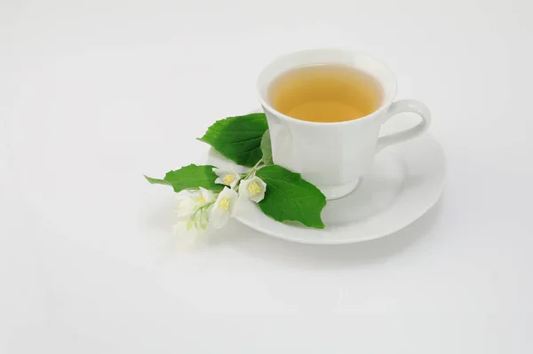 Tazza bianca di tè al gelsomino verde tradizionale con fiori di gelsomino su sfondo bianco — Foto Stock