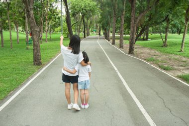 Kadın ve çocuk patika ve geçit kamu parki ve duygu mutluluk üzerinde yürüyen ve keyfini çıkarın.