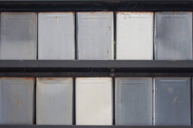 Kullanılan teneke kutu gıda konteyner satırlarının duvarda yeşil bush üzerinde süsleyin..