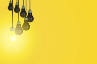 Sarı arka plan ile tavana asılı diğerleri siyah ampul bir sarı ampul.