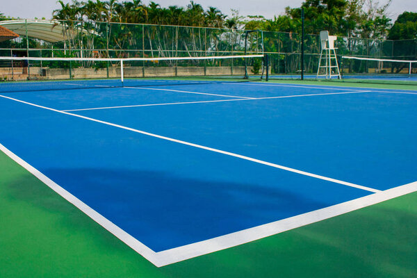 Empty outdoor blue tennis hard court in public park. (Selective focus)