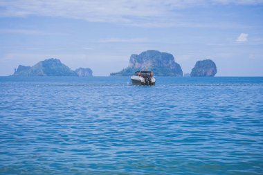 Yaz Tatil Gezisi Kavramı : Yalnız motorlu tekne veya sürat teknesi arka planda ada ile okyanusta yüzen.