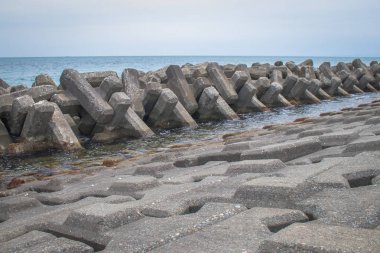 Kıyı sularında dalga hareketinin yoğunluğunu azaltmak ve kıyı erozyonunu azaltmak veya güvenli bir şekilde sağlamak için prefabrik çimento bloklarından inşa edilen dalgalı kıyı koruması. 