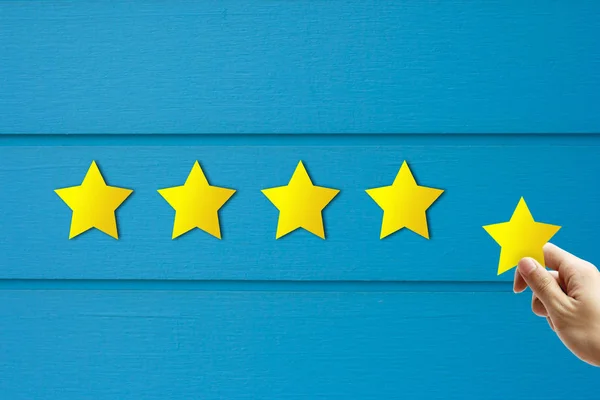 Customer Feedback Concept : Hand holding and giving yellow star for best service ranking.