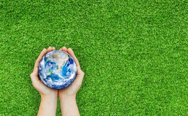Ekoloji ve Çevre Konsepti: El 'in mavi gezegeni yeşil çimlerin üzerinde tutuşu. (NASA tarafından desteklenen bu görüntünün elementleri.)
