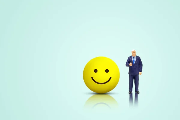 Customer Feedback and Satisfaction Concept : Miniature figure people as businessman standing and showing thumb up nearly smiley icons symbol.