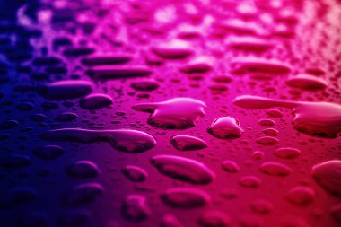 Yerdeki kırmızı ve mavi ışıklandırma efektli su damlasının soyut resmi.