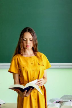 Tahtaya yakın elinde kitap olan bir öğrenci