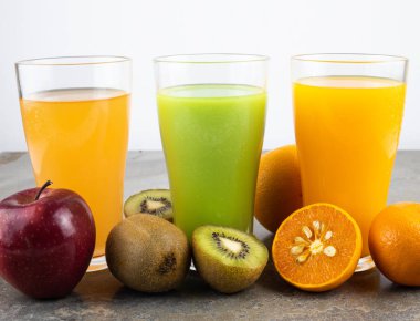 natürmort fotoğraf arka plan üzerinde bardaklarda elma, kivi ve portakal suyu.