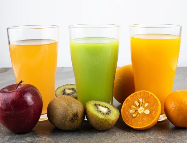 natürmort fotoğraf arka plan üzerinde bardaklarda elma, kivi ve portakal suyu.