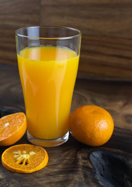 still life photo of orange juice, orange smoothie in glass on wooden background.
