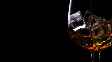 Ağır çekimde buz küpleri ile bir bardak içine silah, siyah bir arka plan üzerinde closeup dökme viski. Konsept: alkol, ruhları, için iyi akşamlar, iyi geceler, alkol sağlık zarar verir..