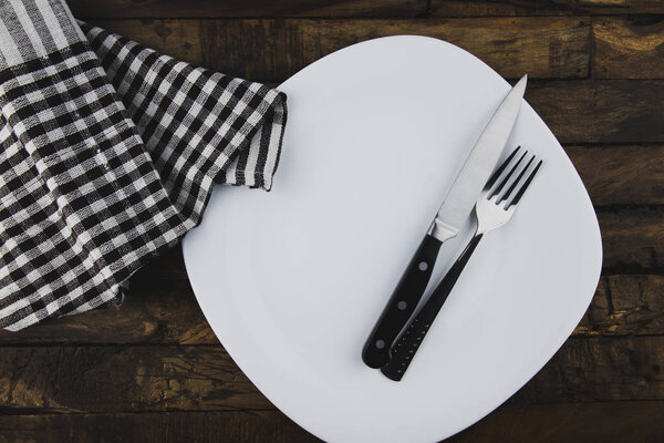 Top view of empty white food plate with fork and knife