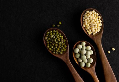 fasulye, yeşil bezelye, mercimek tahta kaşıklar üzerinde ahşap arka plan izole Tarih koleksiyonu kümesi. 