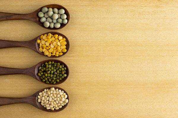 набор бобов, зеленого гороха, чечевицы на деревянных ложках, изолированных на деревянном фоне
. 