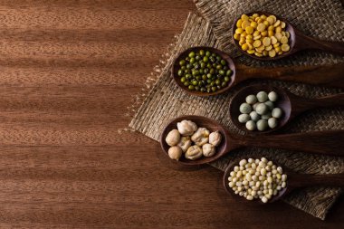 fasulye, yeşil bezelye, mercimek tahta kaşıklar üzerinde ahşap arka plan izole Tarih koleksiyonu kümesi. 