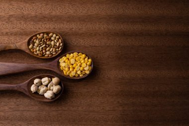 fasulye, yeşil bezelye, mercimek tahta kaşıklar üzerinde ahşap arka plan izole Tarih koleksiyonu kümesi. 