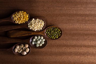 fasulye, yeşil bezelye, mercimek tahta kaşıklar üzerinde ahşap arka plan izole Tarih koleksiyonu kümesi. 