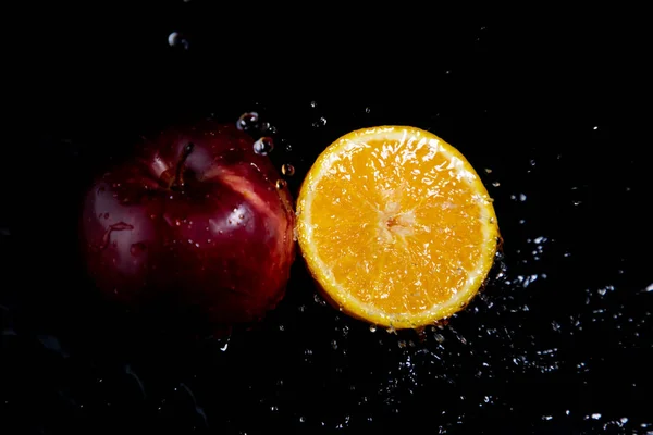orange and red apple splash on black background