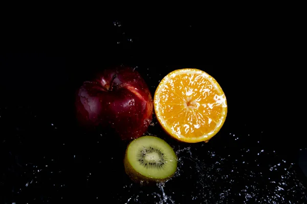 Manzana Roja Naranja Kiwi Salpicaduras Sobre Fondo Negro —  Fotos de Stock