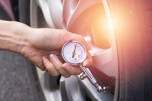 Checking car tyre pressure with gauge