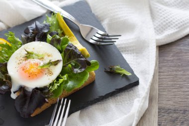 Siyah plaka marul üzerinde ekmek tost ile kızarmış yumurta.