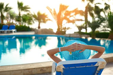 Rahatlatıcı bir tembel yakınındaki lüks yaz yüzme havuzumuz, seyahat zaman kavramı üzerinde şapkalı kadın