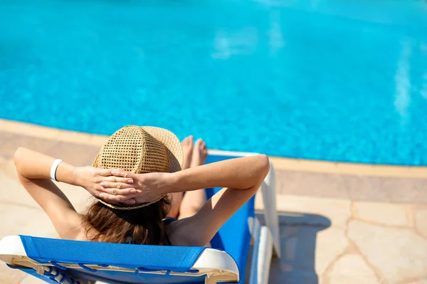 Frau mit Strohhut entspannt in der Nähe eines luxuriösen Sommerpools, Konzeptzeit, um mit Platz für Ihren Text zu reisen — Stockfoto