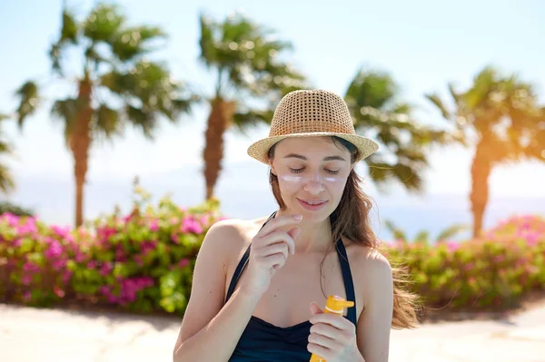 Güzel bir genç kadının portresi, mayoyla gülümseyen yüz güneş koruma kremi şapkalı ile deniz arka plan üzerine sürülür. Konsept: deniz güneş ve tatil özgürlük, güneş yanığı ısı sıcak zevk seyahat — Stok fotoğraf