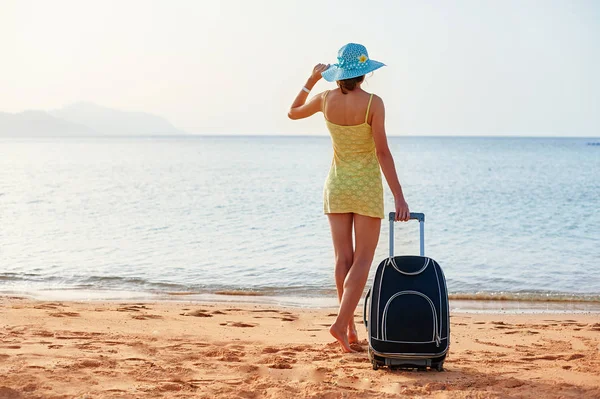 美丽的年轻妇女站在与手提箱在美妙的海背景, 时间的概念旅行 — 图库照片