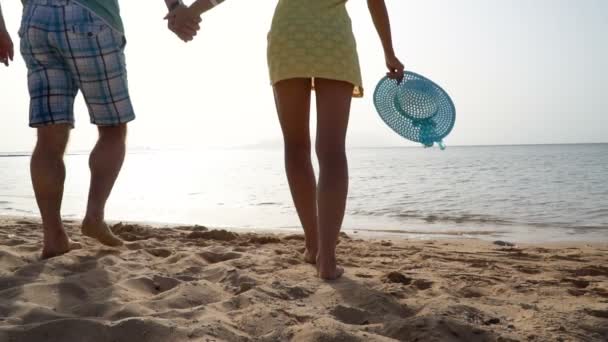 Couple actif courant sur une plage de sable jaune avec ciel bleu et mer en arrière-plan — Video