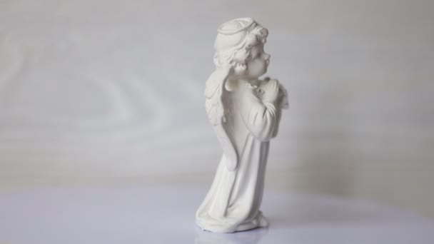 Bílý anděl socha se točí na stojan bílé dřevěné zdi. 4 k video formátu — Stock video