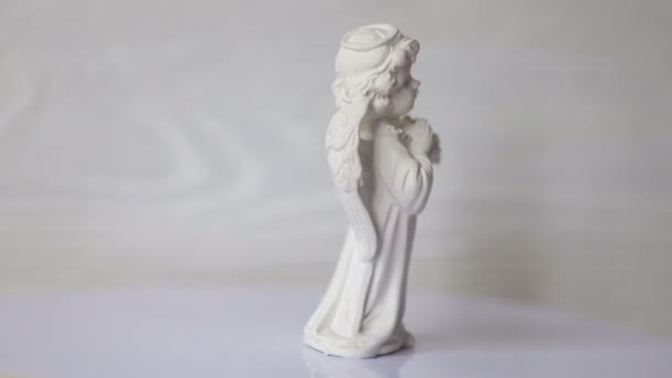 Estatua de ángel blanco gira en un soporte contra una pared de madera blanca. 4k formato de vídeo — Vídeo de stock