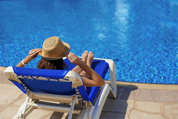 밀 짚 모자 근처 호텔에서 고급 스러운 여름 수영장 갑판의 자에 편안한 여자, 개념 여행 시간 — 스톡 사진