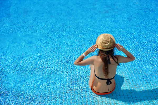 Frau mit Strohhut entspannt auf Liegestühlen in der Nähe eines luxuriösen Sommerpools im Hotel, Konzeptzeit zum Reisen — Stockfoto