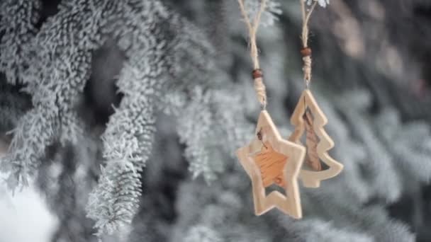 Brinquedos de Natal de madeira pendurados nos ramos da árvore de Natal nevada. vídeo movimento hd — Vídeo de Stock