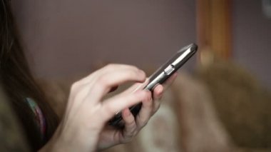 Telefonunuzun ve evde kanepede oturan güzel ve genç birbayan. Kadın sörf web, sosyal ağlar, online mağazasında bir şeyler arıyorum. Kapalı