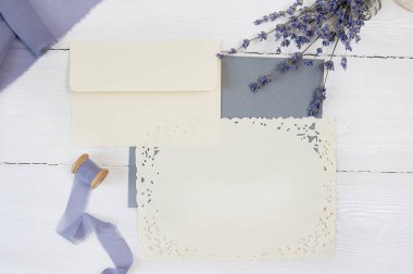 Beyaz boş kartı, zarf ve kumaş pembe ve mavi bir arka plan üzerinde kurdele lavanta çiçekleri beyaz bir arka plan ile. Mockup zarf ve boş kartı ile. Düz yatıyordu. Üstten görünüm