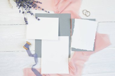 Bir arka plan ile lavanta çiçekleri pembe kumaş üzerine iki wedding rings ve kaligrafi kalemi beyaz bir arka plan üzerinde beyaz boş kartı. Mockup zarf ve boş kartı ile. Düz yatıyordu. Üstten görünüm