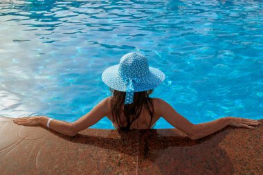yüzme havuzu yaz aylarında açık havada kenarına, kavramı relax ve seyahat üzerinde oturan şapkalı güzel kadın