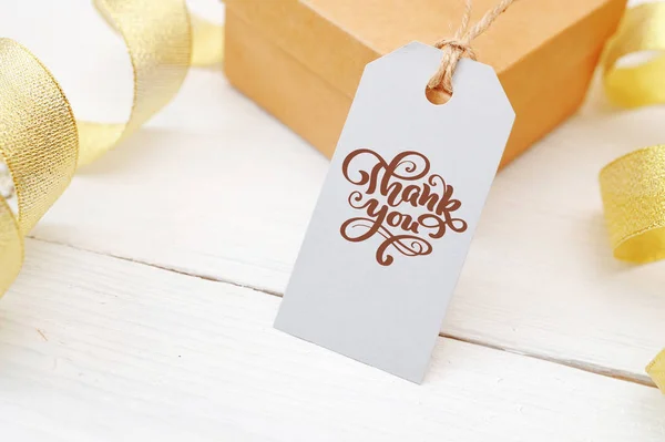 Mockup gift en lege code met kalligrafische tekst dank u op witte houten achtergrond met gouden lint. Belettering van Thanksgiving Day — Stockfoto