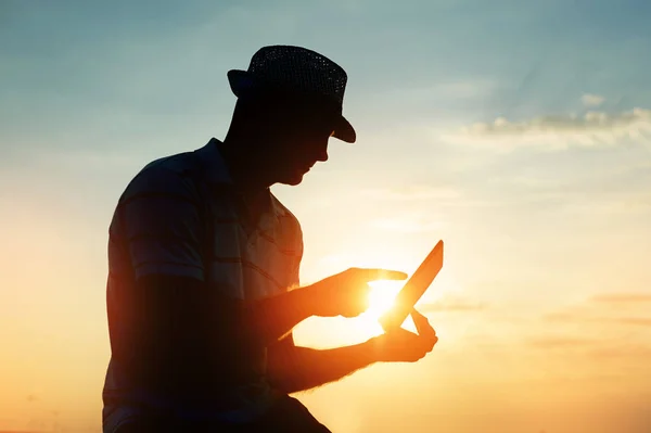 Silhouette Mann arbeitet mit seinem Laptop am Strand während des Sonnenuntergangs, freiberufliches Reisekonzept — Stockfoto