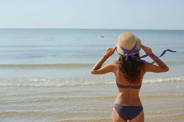Sommer-Lifestyle-Porträt einer hübschen jungen, sonnengebräunten Frau mit Hut. Das Leben genießen und am Strand sitzen, Zeit zum Reisen. Blick auf das Meer — Stockfoto