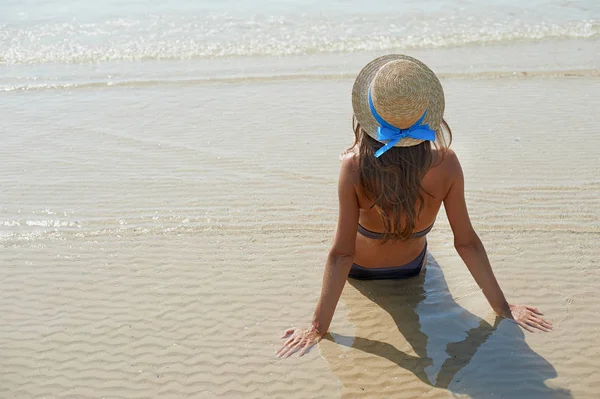 Estilo de vida de verão retrato de mulher muito jovem bronzeada em um chapéu. Aproveitando a vida e sentado na praia, tempo para viajar. Olhando para o mar — Fotografia de Stock