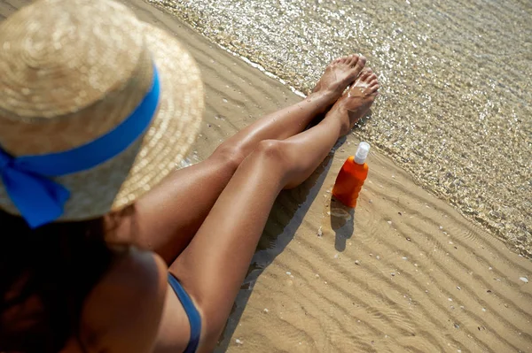 Όμορφη, περιποιημένη γυναικεία πόδια με μια κρέμα για την προστασία ηλιακό έγκαυμα από τον ήλιο το καλοκαίρι στη θάλασσα φόντο. Νοιάζεται για καθαρό και απαλό δέρμα. Κενή θέση για ένα κείμενο — Φωτογραφία Αρχείου